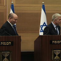 Prime Minister Naftali Bennett, left, and Foreign Minister Yair Lapid, leave the podiums after a joint statement at the Knesset in Jerusalem, June 20, 2022 (AP Photo/Maya Alleruzzo)