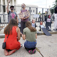 Anti-abortion activists Maggie Donica, 21, left, and Grace Rykaczewski, 21, kneel and pray in front of abortion-rights activists following the Supreme Court's decision to overturn Roe v. Wade, federally protected right to abortion, in Washington, Friday, June 24, 2022. (AP/Jacquelyn Martin)