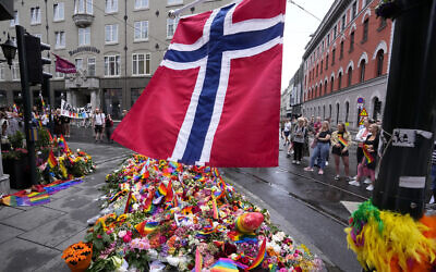 A Norwegian national flag flutters over flowers and rainbow flags that are placed at the scene of a shooting in central of Oslo, Norway, June 26, 2022. (AP Photo/Sergei Grits)
