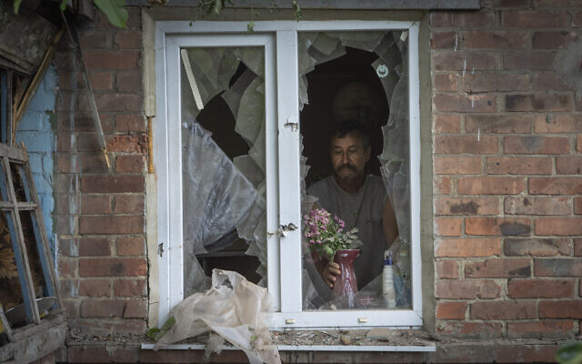 A local resident places a vase with flowers on a broken window in his house damaged by the Russian shelling in Bakhmut, Donetsk region, Ukraine, June 26, 2022.(AP Photo/Efrem Lukatsky)
