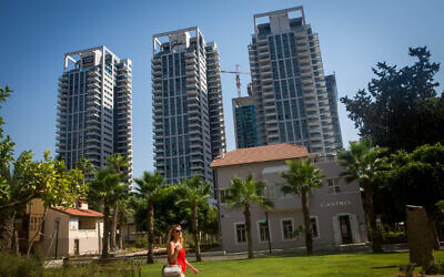 A young woman walks in front of residential towers in Tel Aviv's Sarona neighborhood in Tel Aviv, August 18, 2015. (Miriam Alster/Flash90)