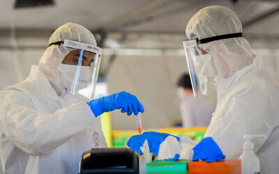 Magen David Adom medical team members at a drive-through coronavirus testing site in Tel Aviv, on March 22, 2020 (Flash90)