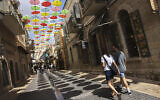 People walk in central Jerusalem where the municipality hung coloful umbrellas to create shade for passersby, on September 10, 2021. (Nati Shohat/Flash90)