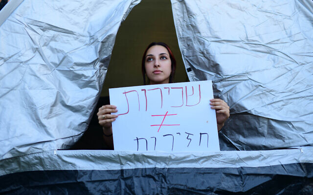 Israelis set up tents on Rothschild Boulevard in Tel Aviv, to protest against the soaring housing prices in Israel and social inequalities, on June 19, 2022. The placard protests soaring rental prices, and translates roughly as "Landlords need not be pigs" (Tomer Neuberg/ Flash90)