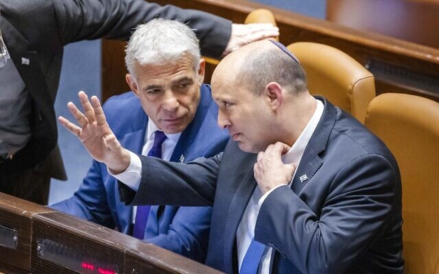 Prime Minister Naftali Bennett and Foreign Minister Yair Lapid speak ahead of the preliminary reading of a bill to dissolve the Knesset, on June 22, 2022. (Olivier Fitoussi/Flash90)