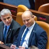 Foreign Minister Yair Lapid (left), the incoming interim prime minister, and outgoing premier Naftali Bennett (right) sit in the Knesset during voting to dissolve parliament for new elections, on June 30, 2022. (Olivier Fitoussi/Flash90)