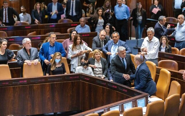Foreign Minister Yair Lapid (left), the incoming interim prime minister, and outgoing premier Naftali Bennett (right) in the Knesset, following a vote to dissolve parliament for new elections, on June 30, 2022. (Olivier Fitoussi/Flash90)