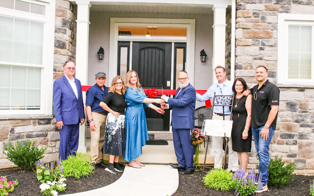 Rabbi Yosef Lipsker, fourth from left, cuts the ribbon on the Caron Treatment Center, a nonprofit rehabilitation center for people struggling with substance abuse. (Courtesy)