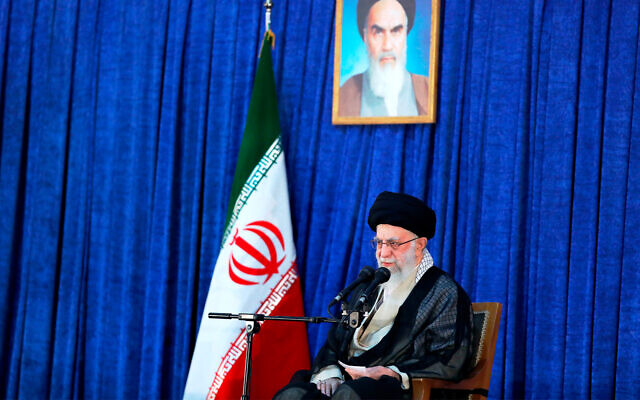 Iranian Supreme Leader Ayatollah Ali Khamenei speaks on the anniversary of the death of the late founder of the Islamic Republic, Ayatollah Ruhollah Khomeini, shown in the poster at top center, at his mausoleum in Tehran, Iran, June 4, 2022. (Office of the Iranian Supreme Leader via AP)