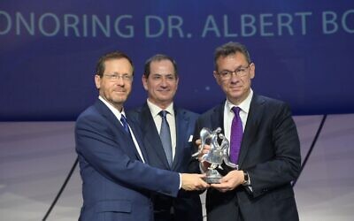 Dr Albert Bourla (right) receives the 2022 Genesis Prize from Israel's President Isaac Herzog, left, and Stan Polovets, co-founder and chairman/CEO of the Genesis Prize Foundation. (Amos Ben-Gershom/GPO)