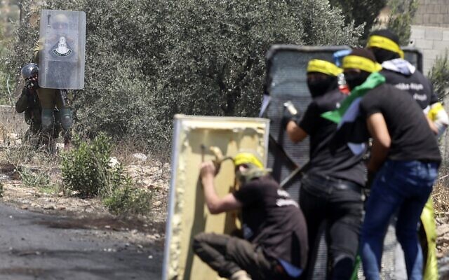 Illustrative: Palestinians use makeshift barriers during clashes with Israeli forces following a demonstration in the village of Kfar Qaddum, near the Jewish settlement of Kedumim in the West Bank, on July 1, 2022. (Jaafar Ashtiyeh/AFP)