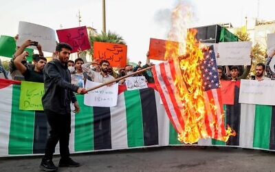 An Iranian student from the Islamic Basij volunteer militia burns a US flag in Tehran, on July 16, 2022, during a protest against US President Joe Biden's visits to Israel and Saudi Arabia (ATTA KENARE / AFP)
