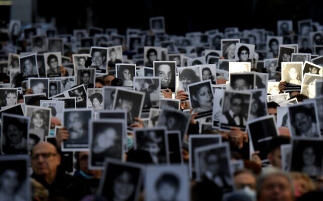 Relatives of victims of a bomb attack at the Jewish community center of the Mutual Israelite Association of Argentina (AMIA) that killed 85 people and injured 300, hold photos during its 28th anniversary, in Buenos Aires, Argentina, on July 18, 2022. (Luis ROBAYO / AFP)