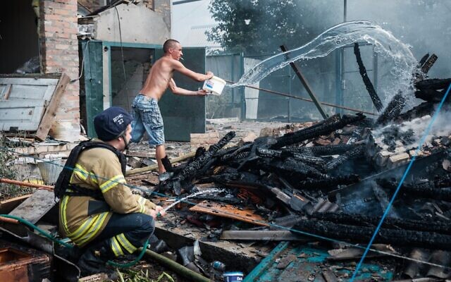 A local resident helps firefighters to put out a fire in a yard of a house in the town of Bakhmut following an airstrike on July 19, 2022, amid the Russian invasion of Ukraine. (Igor TKACHEV / AFP)