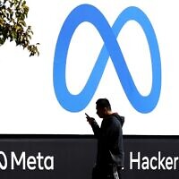 A pedestrian walks in front of a new logo and the name 'Meta' on the sign in front of Facebook headquarters in Menlo Park, California, on October 28, 2021. (Justin Sullivan/ Getty Images North America/ AFP/ File)