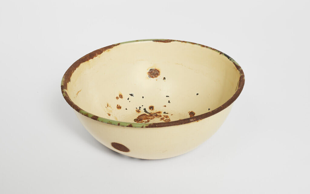 An enamel bowl, on display at the Museum of Jewish Heritage in Manhattan, was carried through three concentration camps by the Burbea family from Libya, even serving as a vessel to carry their youngest son to his circumcision when he was born in Bergen-Belsen in 1944. (Museum of Jewish Heritage/ via JTA)