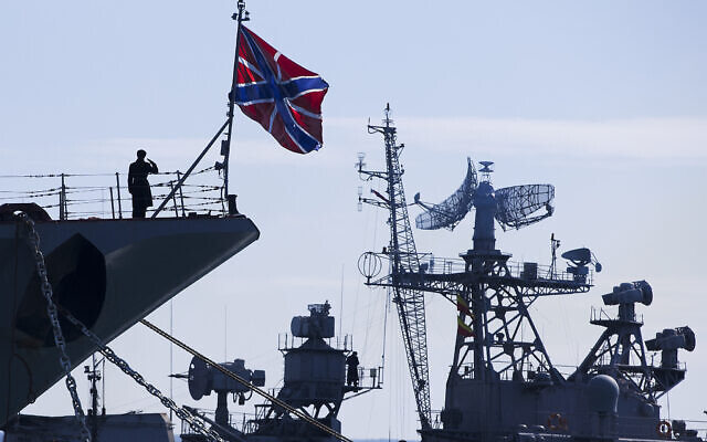 A Russian sailor salutes on the bow of Missile Cruiser Moskva, left, as crew of Russian patrol ship Pitliviy, right, prepare to moor the vessel, in Sevastopol, Crimea, March 30, 2014. (AP Photo/Pavel Golovkin, File)