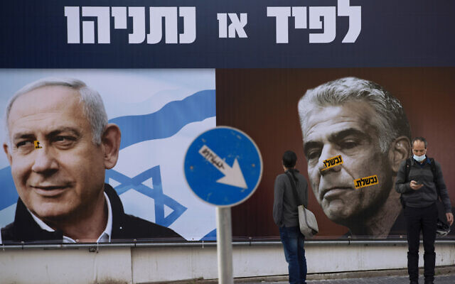 Illustrative image: People stand in front of an election campaign billboard for the Likud party showing a portrait of its leader former prime minister Benjamin Netanyahu, left, and current Prime Minister Yair Lapid, in Ramat Gan, Israel, March 14, 2021. AP Photo/Oded Balilty, File)