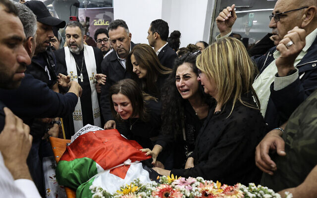 Colleagues and friends react as the Palestinian flag-draped body of veteran Al Jazeera journalist Shireen Abu Akleh is brought to the news channel's office in the West Bank city of Ramallah, Wednesday, May 11, 2022. (Abbas Momani/Pool via AP, File)