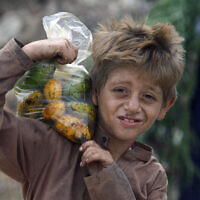 An Afghan refugee boy carries a bag of mangoes on his shoulder in Karachi, Pakistan, June 19, 2022. (AP Photo/Fareed Khan)