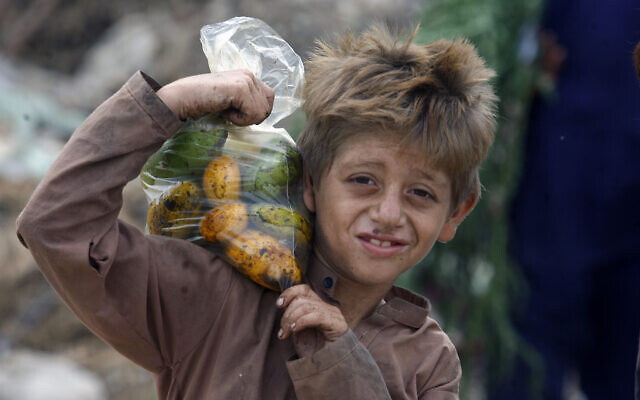 An Afghan refugee boy carries a bag of mangoes on his shoulder in Karachi, Pakistan, June 19, 2022. (AP Photo/Fareed Khan)