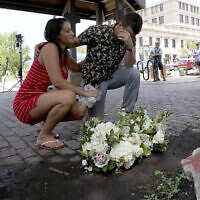 Brooke and Matt Strauss, who were married a day earlier, pause after leaving their wedding bouquets in downtown Highland Park, Ill., near the scene of a mass shooting, on July 5, 2022, in Highland Park, Ill. (AP Photo/Charles Rex Arbogast)