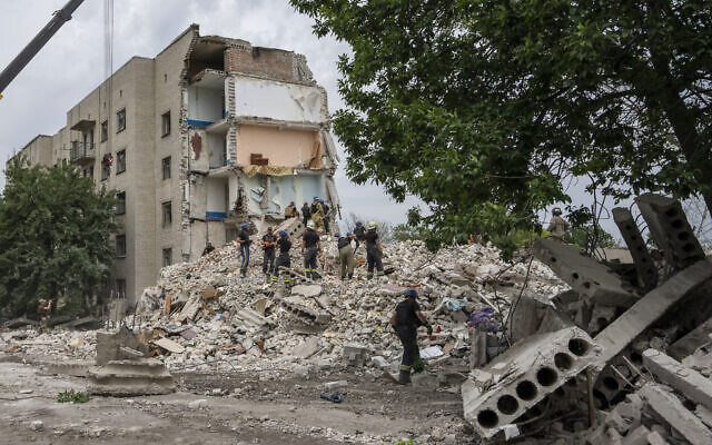 Rescue workers stand on the rubble at the scene in the after math of a missile strike that his a residential apartment block, in Chasiv Yar, Donetsk region, eastern Ukraine, July 10, 2022. (AP Photo/Nariman El-Mofty)