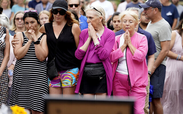 Four women join local residents for a two-minute moment of silence at 10:14 a.m. at the Highland Park, Illinois memorial commemorating the seven people who lost their lives during the town's Fourth if July parade, July 11, 2022. (AP Photo/Charles Rex Arbogast)