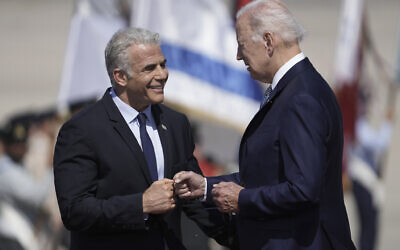 US President Joe Biden, right, is greeted by Prime Minister Yair Lapid, as they fist bump during a welcoming ceremony at Ben Gurion Airport, near Tel Aviv, July 13, 2022. (AP Photo/Ariel Schalit)