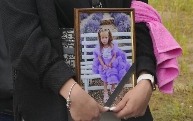 A woman carries a portrait of Liza, 4-year-old girl killed by Russian attack, during a funeral ceremony in Vinnytsia, Ukraine, July 17, 2022. (AP Photo/Efrem Lukatsky)