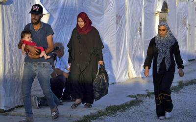 Syrian refugee families walk back into a refugee camp after running errands in the town of Bar Elias, in the Bekaa Valley, Lebanon, July 7, 2022. (AP Photo/Bilal Hussein)