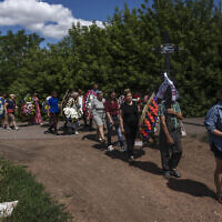 Family and friends of 35-year-old Anna Protsenko, who was killed in a Russian rocket attack, walk to a cemetery for her burial, during her funeral procession, on the outskirts of Pokrovsk, eastern Ukraine, July 18, 2022. (Nariman El-Mofty/AP)
