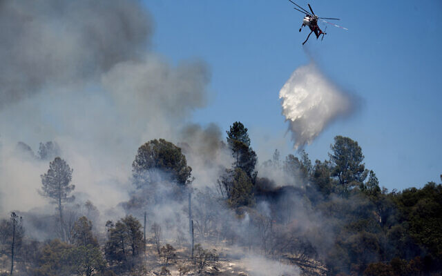 A helicopter drops water on the Oak Fire burning in Mariposa County, California, on July 23, 2022. (AP Photo/Noah Berger)