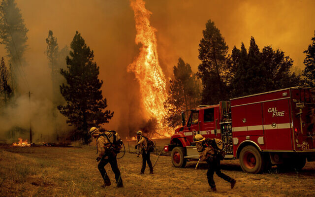 Firefighters work to keep the Oak Fire from reaching a home in the Jerseydale community of Mariposa County, California, July 23, 2022. (AP Photo/Noah Berger)