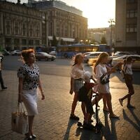 People walk in the light of the setting sun at the end of a hot day in the center of Moscow, Russia, Tuesday, July 26, 2022. (AP/Alexander Zemlianichenko)
