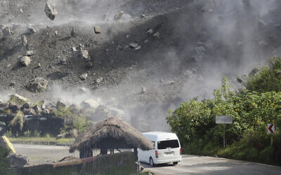 Boulders fall as a vehicle negotiates a road during an earthquake in Bauko, Mountain Province, Philippines on July 27, 2022  (AP Photo/Harley Palangchao)