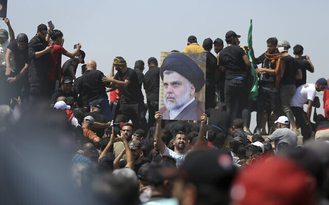 A protester holds a poster depicting Shiite cleric Muqtada al-Sadr on a bridge leading towards the Green Zone area in Baghdad, Iraq, July 30, 2022. (AP/Anmar Khalil)