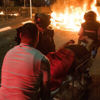 File: Medics evacuate a man injured during riots in Acre, northern Israel, May 12, 2021. (Roni Ofer/Flash90)