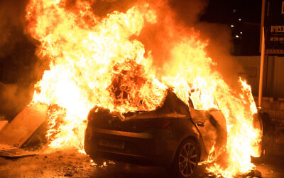 A car burns after being set on fire during riots in Acre, northern Israel, May 12, 2021. (Roni Ofer/Flash90)