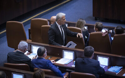Then-Foreign Minister Yair Lapid walks by opposition leader Benjamin Netanyahu in the Knesset on November 8, 2021. (Olivier Fitoussi/Flash90)