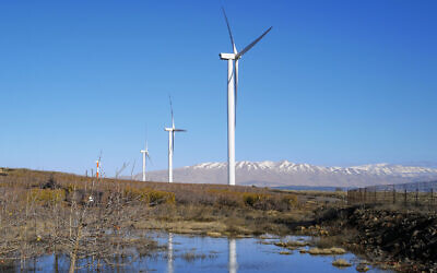 Renewable energy wind turbines as seen next to the snowy peaks of Mount Hermon on January 3, 2021, in the northern Golan Heights. (Michael Giladi/Flash90)
