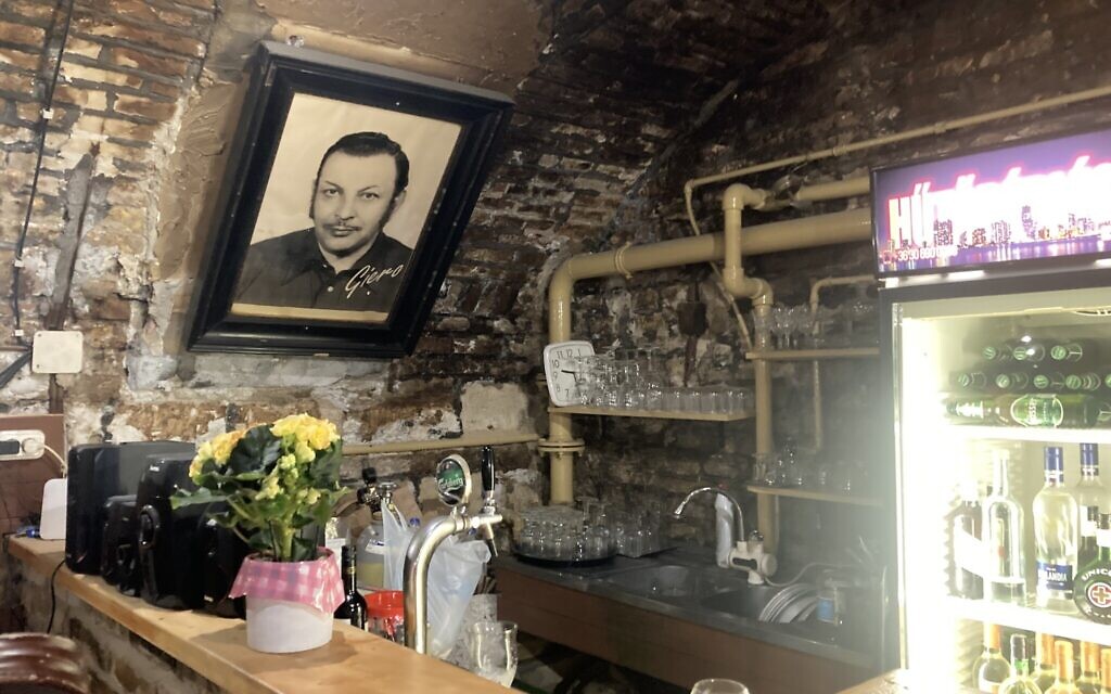 A photo of Gyulane 'Aunt Gizi' Farkas's father, Giero, hangs over the bar at Giero Pub, Budapest, May 12, 2022. (Yaakov Schwartz/ Times of Israel)