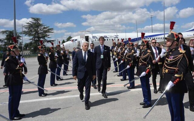 Prime Minister Yair Lapid, center, is greeted at Charles De Gaulle airport in Paris, France, on July 5, 2022. (Amos Ben Gershom/GPO)