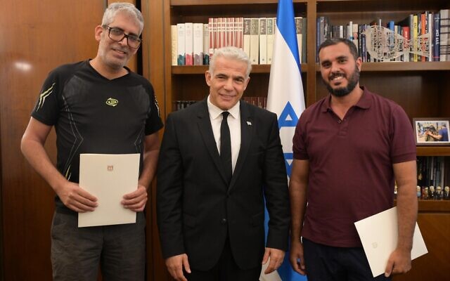 Prime Minister Yair Lapid (center) meets with Haim Naim (right) and Meshi Ben Ami at his office in Jerusalem, July 20, 2022. (Amos Ben-Gershom/GPO)