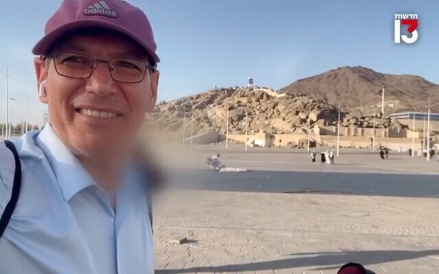 Channel 13 reporter Gil Tamary reports from Mecca on July 17, 2022. The face of the man who assisted him is blurred in the background  (Screen capture/Channel 13)