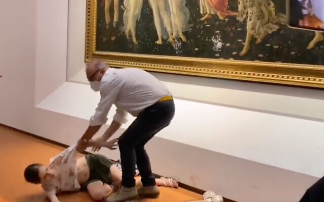 Two environmental activists are removed after gluing their hands to a Botticelli artwork in Florence, Italy, leaving handprints on the canvas's protective glass, July 22, 2022. (Screenshot)