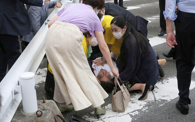 Japan’s former prime minister Shinzo Abe, center, on the ground in Nara, western Japan, July 8, 2022. (Kyodo News via AP)