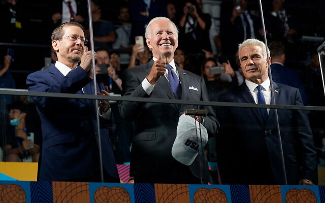 US President Joe Biden gives a thumbs up as he stands behind a glass partition with President Isaac Herzog, left, and Prime Minister Yair Lapid during the opening ceremonies of the Maccabiah Games at Teddy Stadium in Jerusalem, July 14, 2022. (AP Photo/Evan Vucci)