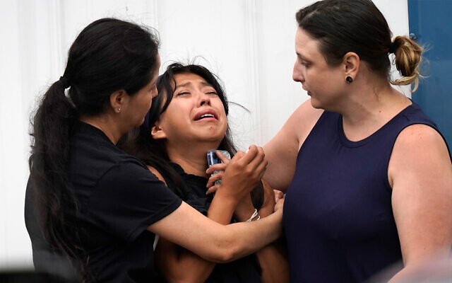 Yesenia Hernandez, center, granddaughter to Nicolas Toledo-Zaragoza, who was killed during a Fourth of July parade earlier in the week in Highland Park., Ill., is comforted outside the Iglesia Emanuel Church during a private family viewing before the funeral service, July 8, 2022, in Waukegan, Ill. (AP Photo/Charles Rex Arbogast)