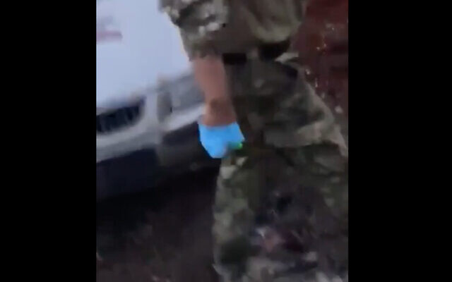 A soldier wears surgical gloves and wields a box knife before he apparently castrates a prisoner in footage circulated online on July 28, 2022. (Screenshot)